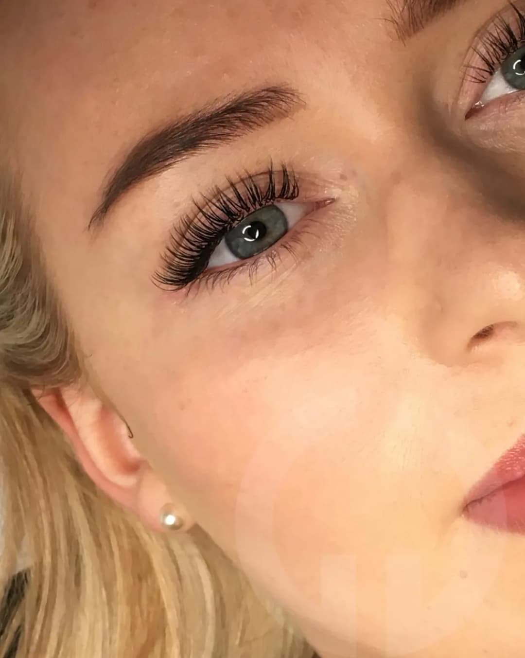 Close-up of eyelash extensions on a blonde woman with light blue eyes